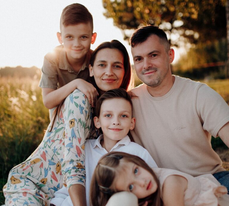 A joyful family sitting together outdoors on a sunny day. Perfect for lifestyle themes.