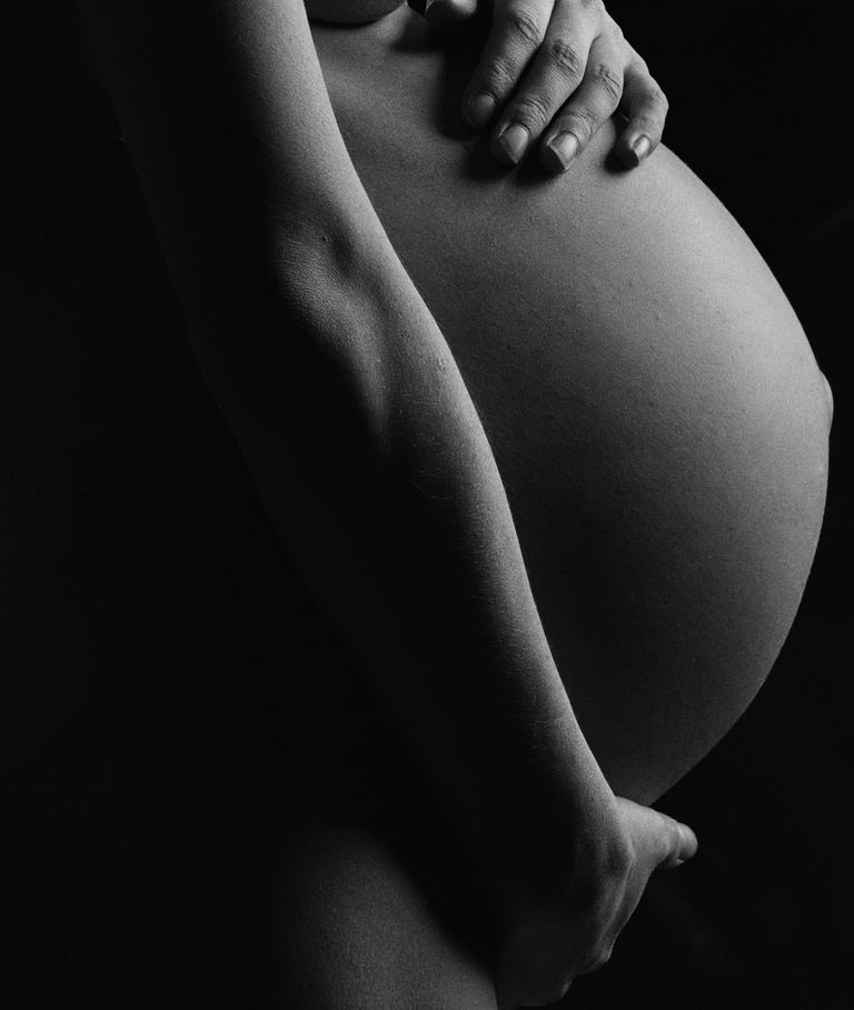 Artistic monochrome close-up of a pregnant woman's belly, showcasing maternal beauty.